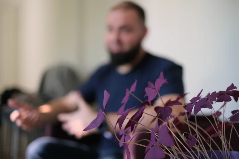 Symbolbild für verdecktes Arbeiten, unscharfe Person hinter scharf abgebildeter Pflanze